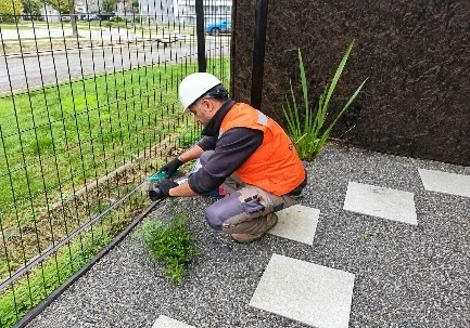 Técnico de B&V Control Plagas instalando una estación cebadera junto a un cerco de jardín